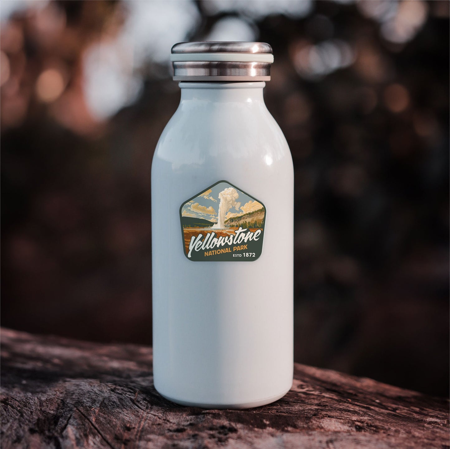 Green and yellow Yellowstone National Park waterproof vinyl sticker on white water bottle against sunset backdrop. Stunning mountain art for outdoor lovers. Ideal for water bottles, Hydroflask, Yeti, laptops, and more.