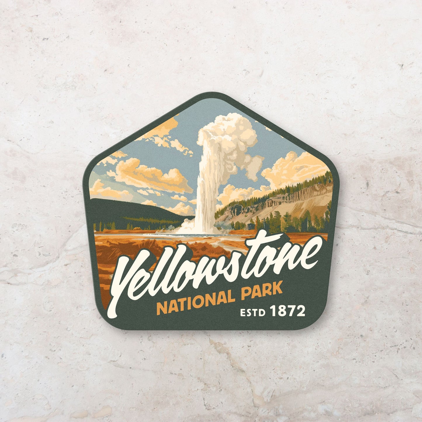 Yellow and green decal of Yellowstone National Park placed on a marble countertop. Features stunning art of a geyser spewing water like what you would see at Old Faithful